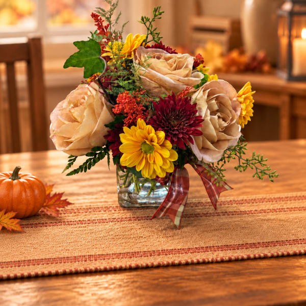 Autumn bouquet of beige roses and yellow chrysanthemums in a glass vase