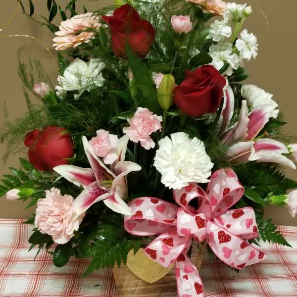 Bouquet of red roses, lilies, and pink flowers with a heart ribbon
