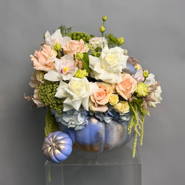 Floral arrangement of roses and orchids in a metallic pumpkin container