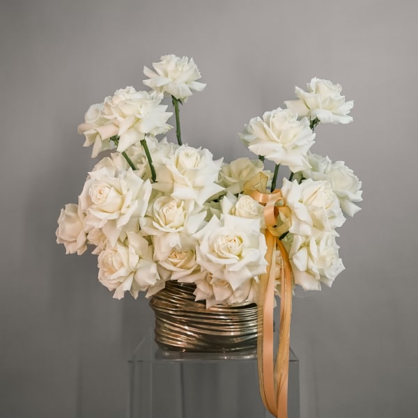 White rose bouquet in a metallic vase with a gold ribbon