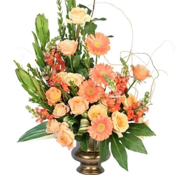 Peach roses and orange gerbera daisies in a gold vase