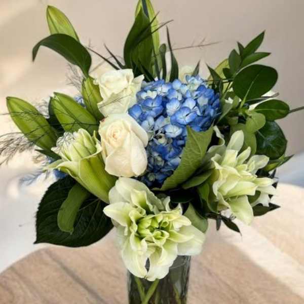 Blue hydrangeas and white roses in a clear glass vase