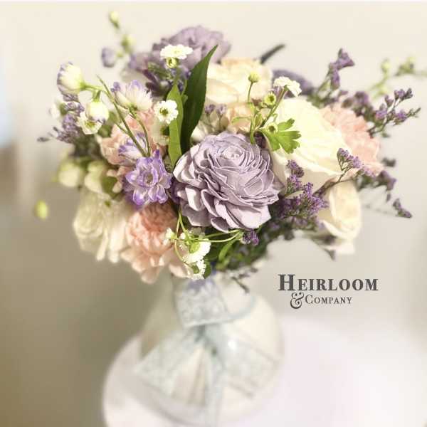 Bouquet of pastel roses and purple flowers tied with a white ribbon