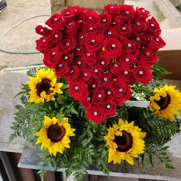 Heart-shaped red rose arrangement with yellow sunflowers and greenery