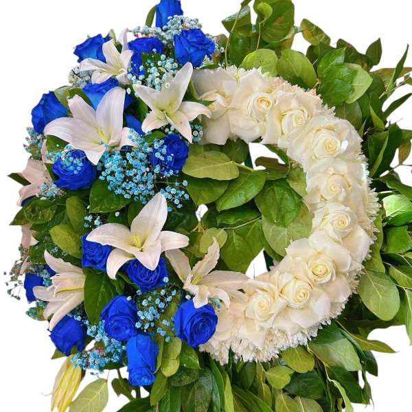 Heart-shaped wreath of blue and white roses with lilies and greenery