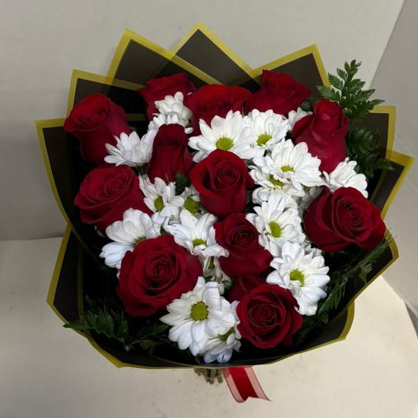 Bouquet of red roses and white daisies wrapped in black paper