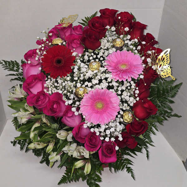 Heart-shaped bouquet of red and pink roses with gerbera daisies and chocolates