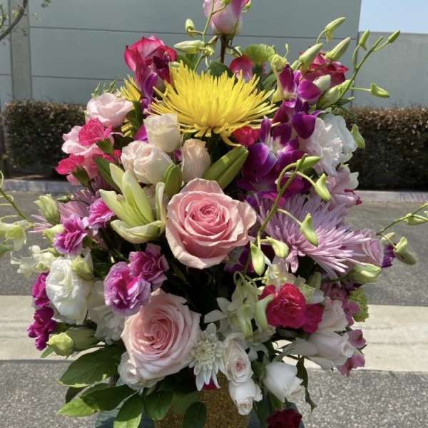 Tall bouquet of pink and white roses with purple orchids and a yellow bloom