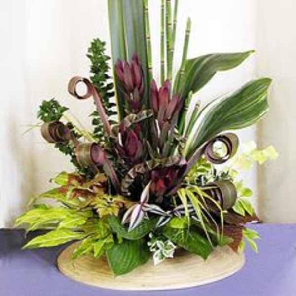Tall tropical arrangement with purple blooms and large green leaves