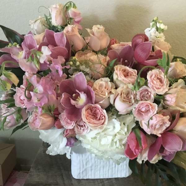 Large pink and peach floral arrangement in a white vase