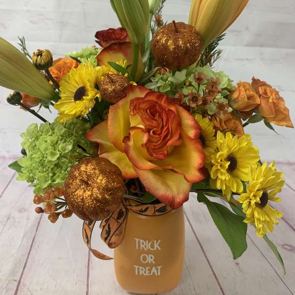 Halloween bouquet with orange roses, yellow daisies, lilies, and glitter pumpkins in a Trick or Treat vase