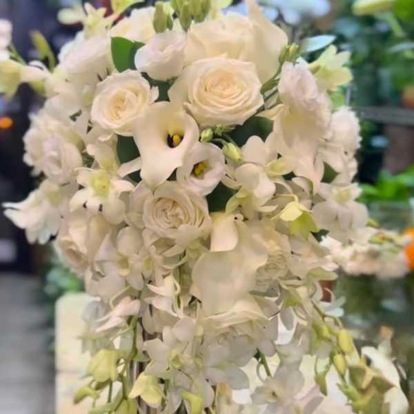 White floral arrangement with cascading orchids and roses in a vase