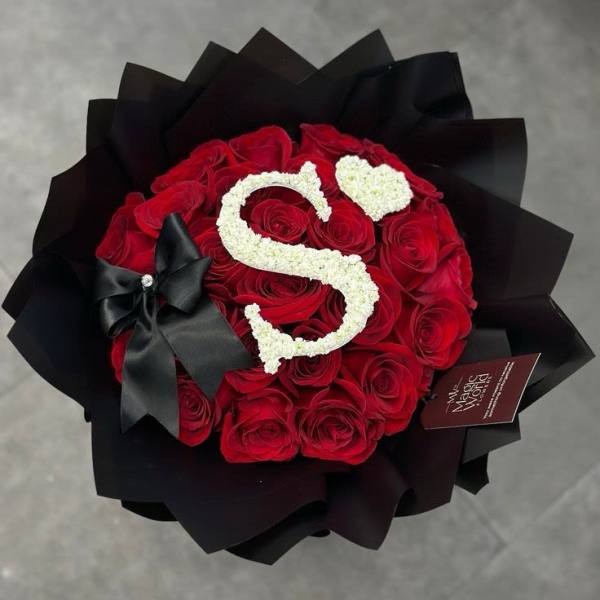 Red rose bouquet with a white floral letter S and black wrapping