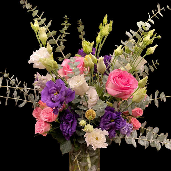 Pink and purple bouquet in a glass vase with eucalyptus