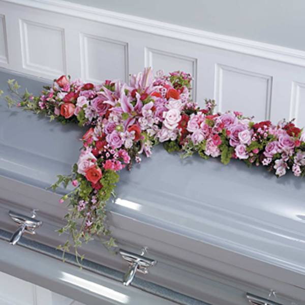 Pink and white floral spray arranged on a silver casket