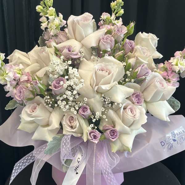 Bouquet of white roses and pale lavender flowers with a ribbon bow
