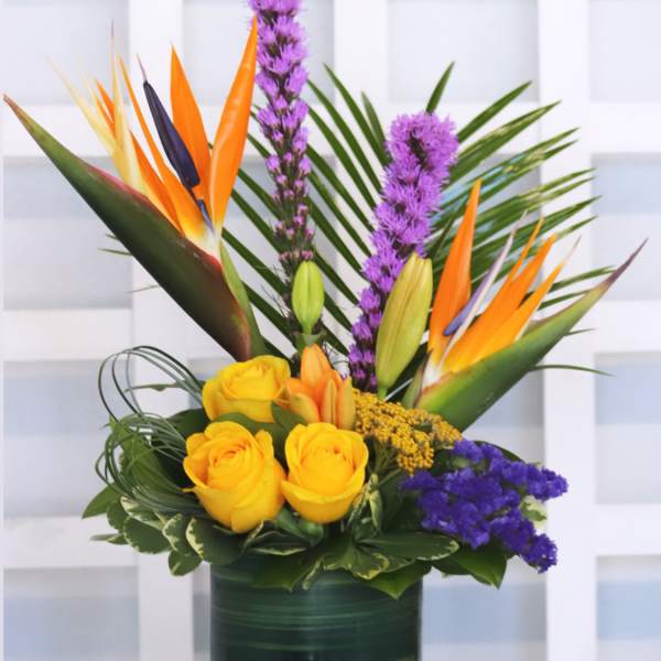 Tropical bouquet with yellow roses and bird of paradise in a green vase