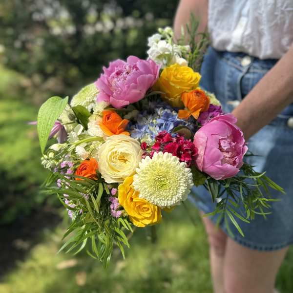 Handheld bouquet of pink, yellow, orange, and white flowers