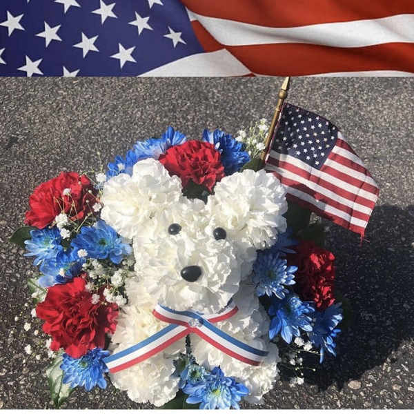 White teddy bear made of flowers with red and blue blooms and a small U.S. flag