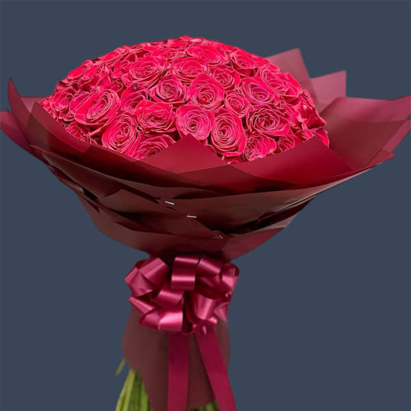 Bouquet of bright pink roses wrapped in burgundy paper with a ribbon