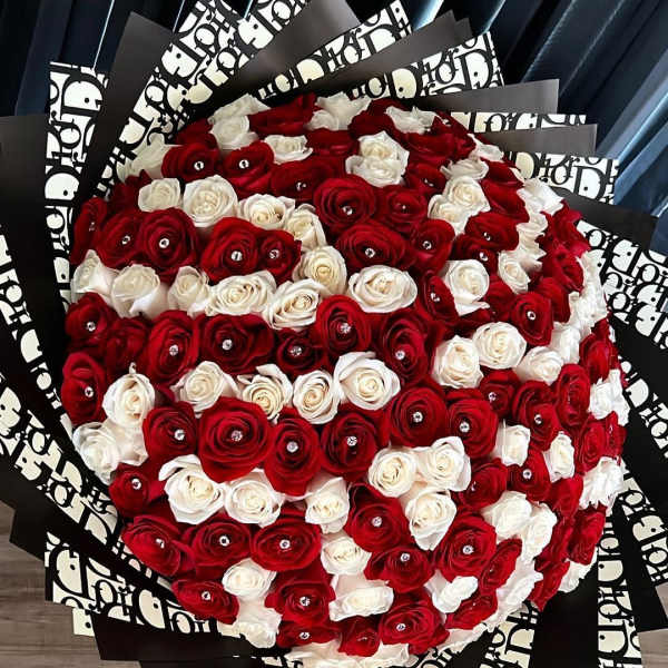 Large bouquet of red and white roses wrapped in black patterned paper