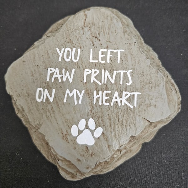 Decorative stone with the words "You left paw prints on my heart" and a paw print
