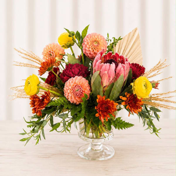 Colorful mixed bouquet in a clear glass pedestal vase