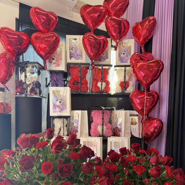 Red rose and carnation arrangements with heart balloons and teddy bear gift bags