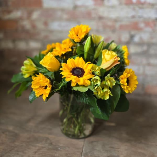 Yellow flowers arranged in a clear glass vase