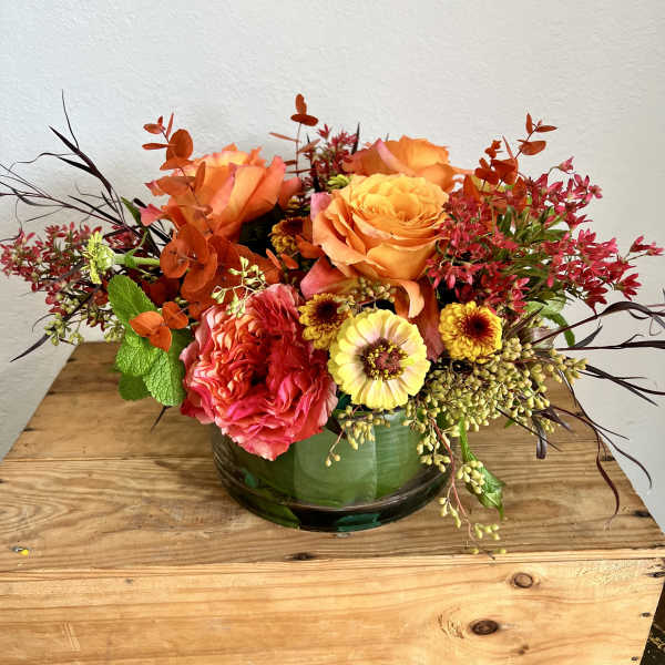 Orange and pink floral arrangement in a glass bowl vase