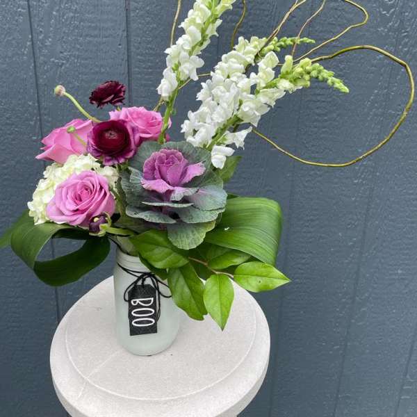 Pink and white floral arrangement in a white vase with looping branches