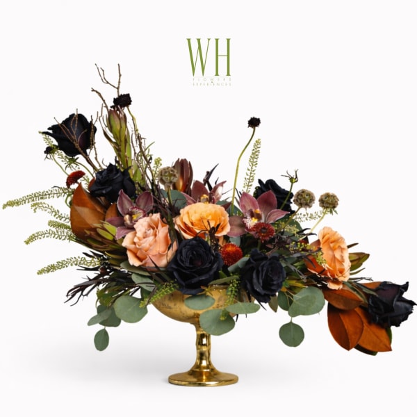 Black and peach floral arrangement in a gold pedestal vase