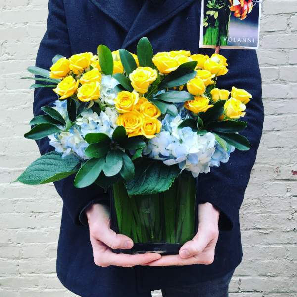 Yellow roses and pale blue hydrangeas in a glass vase