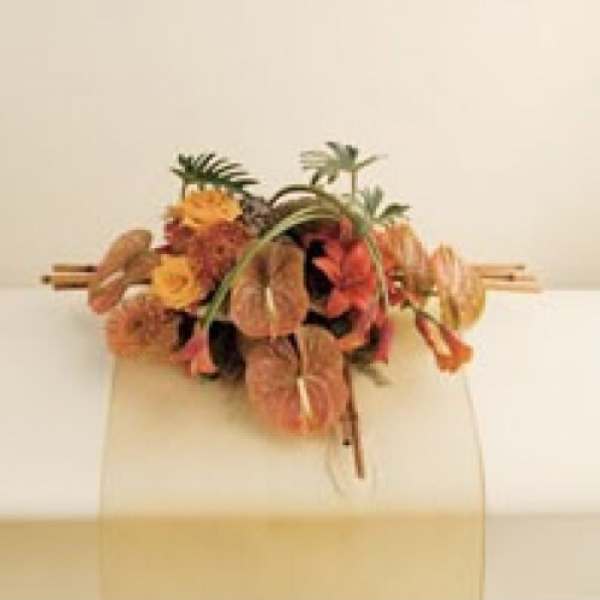 Tropical floral arrangement with orange and yellow blooms on a stand