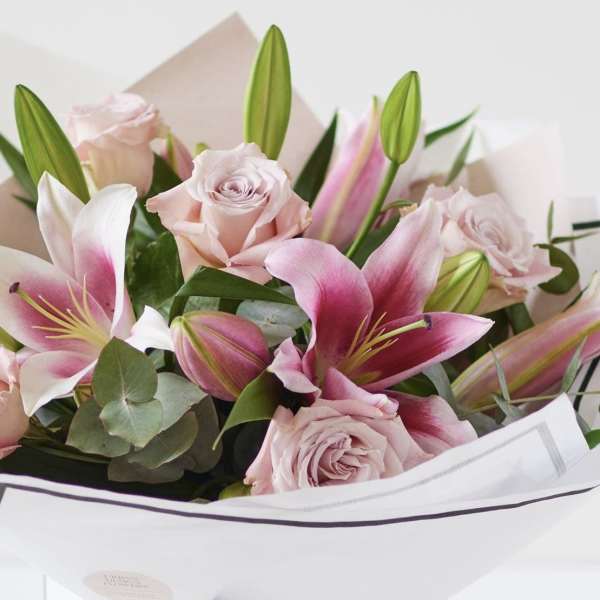Bouquet of pink roses and lilies wrapped in white paper
