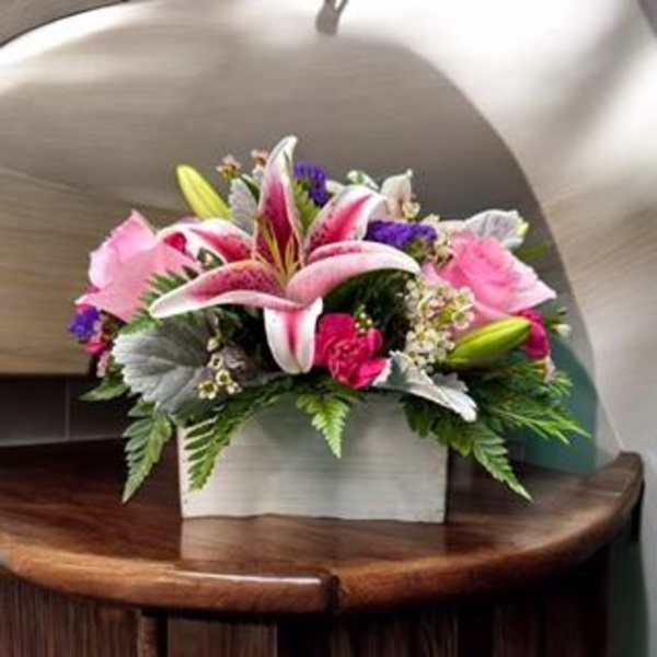 Pink lilies and roses arranged in a white box