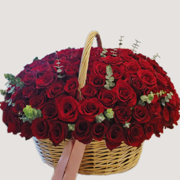 Basket filled with red roses and small eucalyptus sprigs