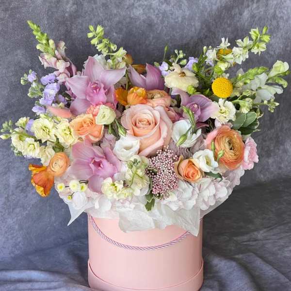 Pastel bouquet in a pink hat box with roses and orchids