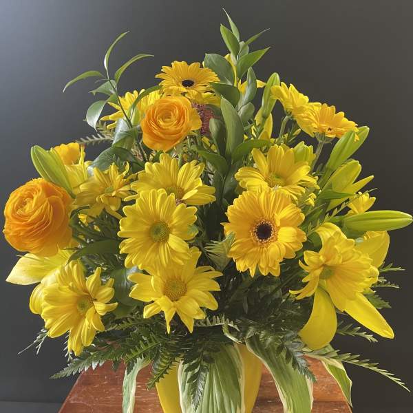 Yellow bouquet with daisies, lilies, and orange roses in a vase