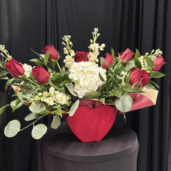 Red roses and white flowers in a red heart-shaped box