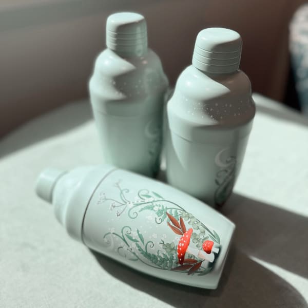 Three mint-colored bottles with floral mushroom artwork