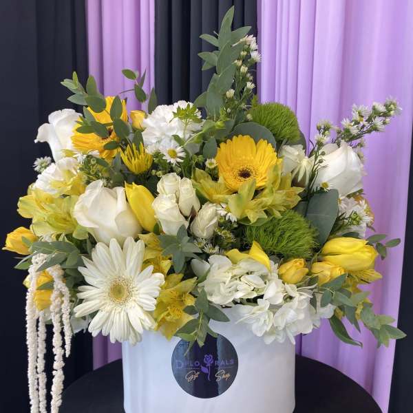 Yellow and white mixed flower arrangement in a white hat box