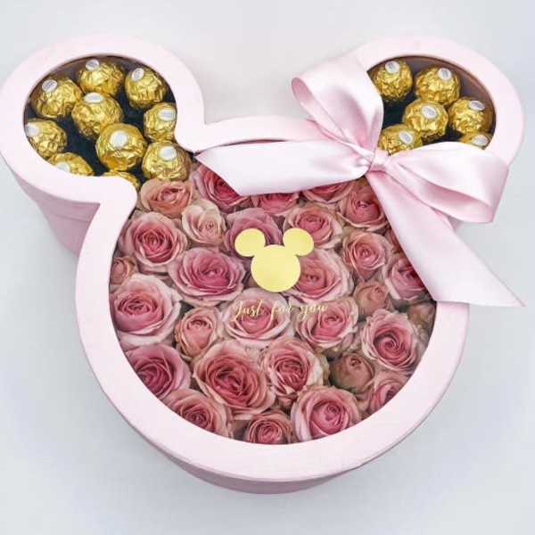 Pink rose arrangement in a Mickey-shaped box with gold chocolates and a ribbon bow