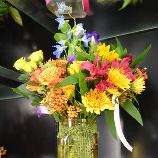 Colorful mixed bouquet in a glass vase with yellow, pink, and blue flowers