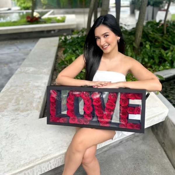 Woman holding a framed LOVE sign filled with red roses