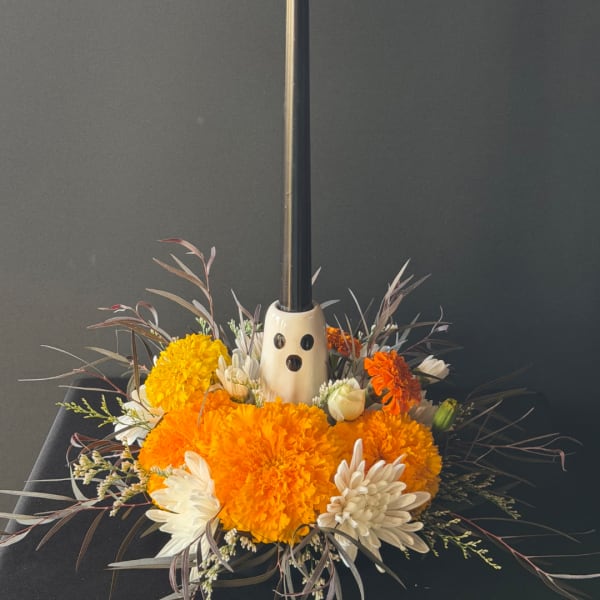 Orange and white floral arrangement with a ghost decoration in a low container