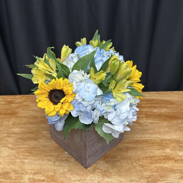 Sunflowers and blue hydrangeas in a square wooden box