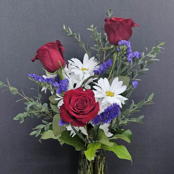 Red roses and white daisies in a glass vase
