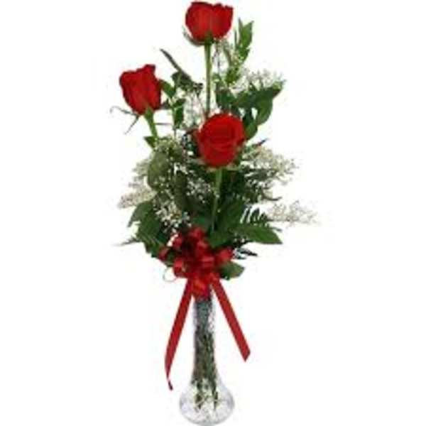 Three red roses in a clear glass vase with a red ribbon