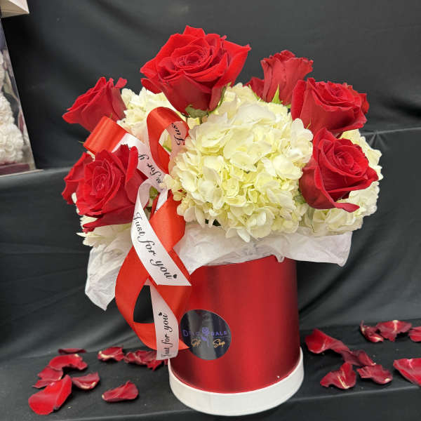 Red roses and white hydrangeas in a red hatbox with ribbon